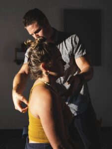 Dr. Tony Miller performing a focused spinal adjustment on a seated patient in warm lighting