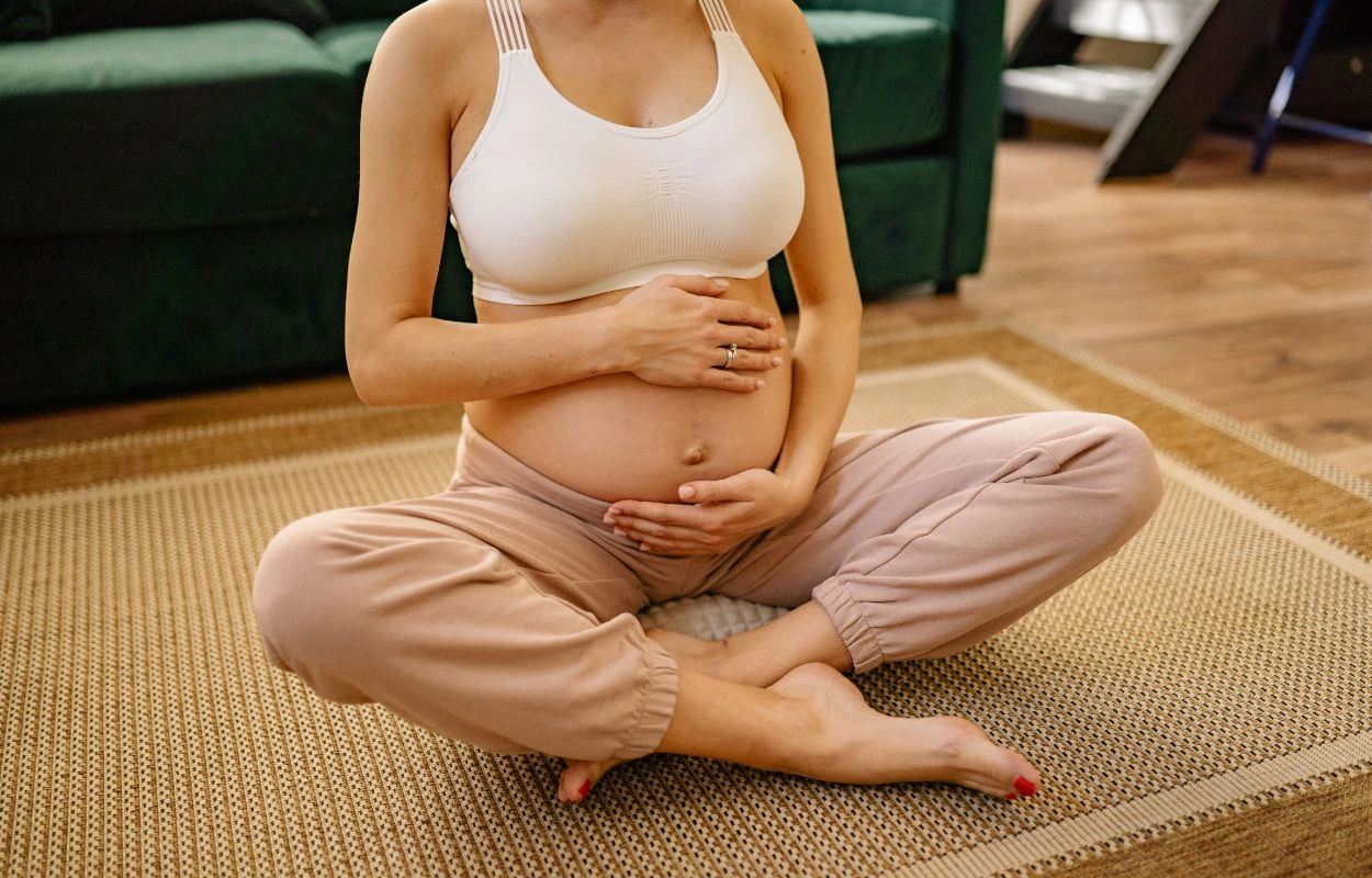 Pregnant woman sitting on the floor holding her lower back from pregnancy sciatica pain