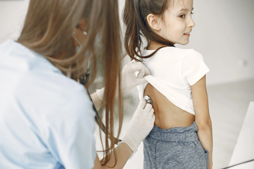 Chiropractor evaluating spinal posture of a young girl during scoliosis treatment