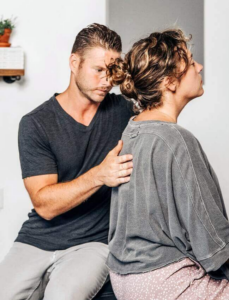 Dr. Tony Miller providing a NetworkSpinal adjustment to a seated patient.