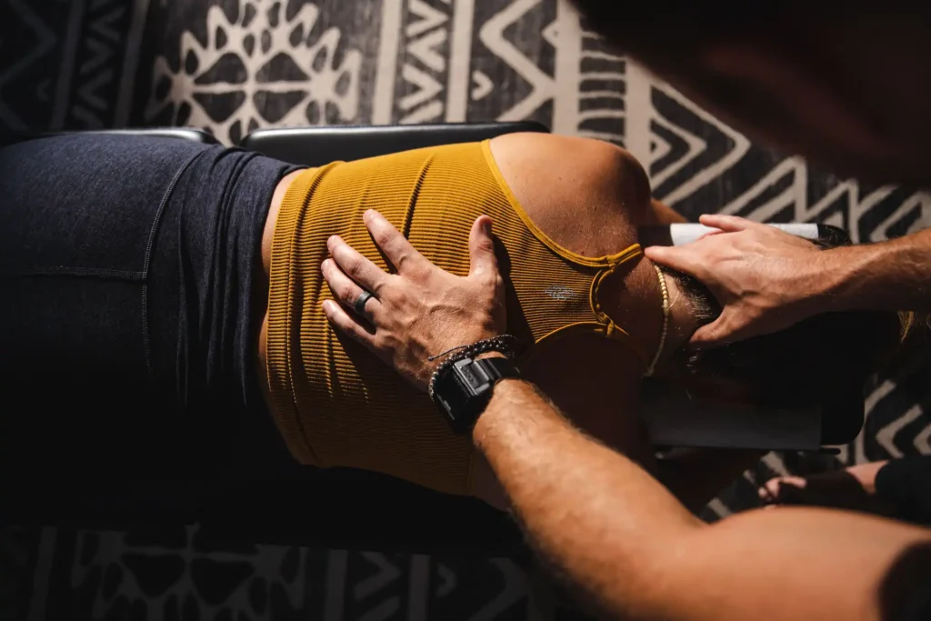 Dr. Tony Miller, chiropractor specializing in life potential, performing a spinal adjustment on a patient lying face down on a treatment table, with his hands positioned on the patient’s upper back and neck.