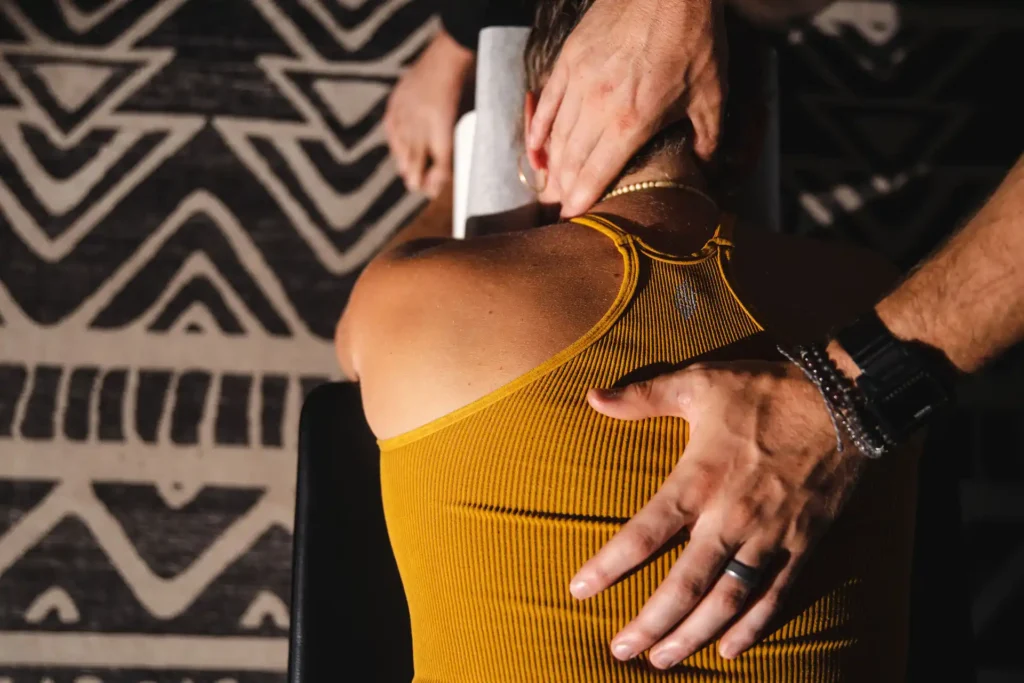 Dr. Tony-Miller, chiropractor specializing in life potential, performing a spinal and neck adjustment on a patient wearing a mustard-yellow top during a chiropractic session.