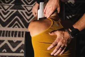 Dr. Tony-Miller, chiropractor specializing in life potential, performing a spinal and neck adjustment on a patient wearing a mustard-yellow top during a chiropractic session.