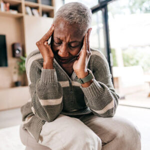Woman in bright room holding head with headache