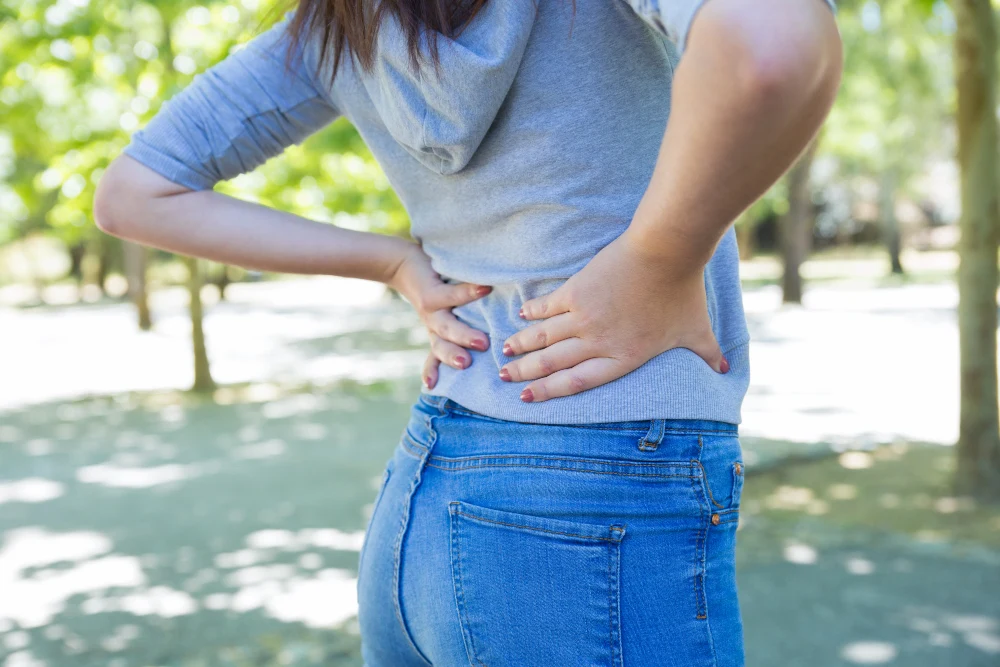 Closeup of young woman touching waist in park