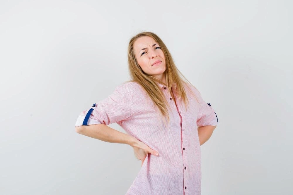 Young woman in a casual pink shirt with severe backache