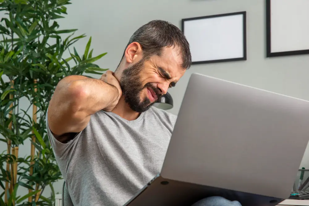 Office worker experiencing neck pain from prolonged desk work
